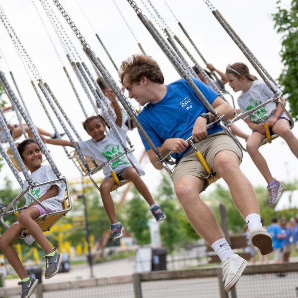 Camp instructor riding on swinging gibbons ride with camp group